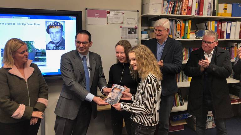 Burgemeester Adriaansen geeft het boek Spion van Oranje aan leerlingen van groep 8