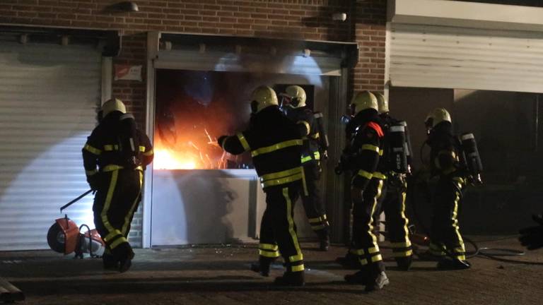 De politie breekt de deuren van de garageboxen open. (Foto: Perry Roovers/SQ Vision)