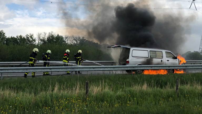 De brandweer is ter plaatse om het in brand gevlogen busje op de A58 te blussen (Foto: Martijn van de Wouw)