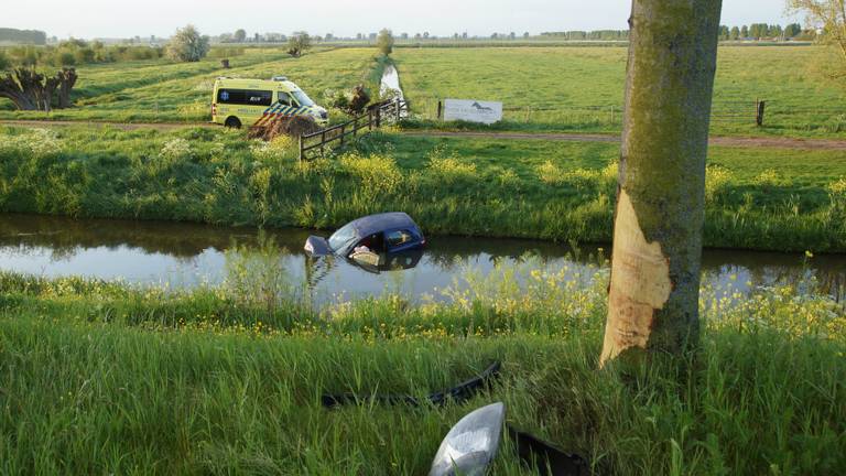 De beschadigde boom, de auto die kopje onder ging en de toegesnelde ambulance (foto: Erik Haverhals/Foto Persbureau Midden Brabant).