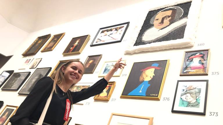 Naomi Donkers wijst naar haar werk in het Rijksmuseum in Amsterdam.