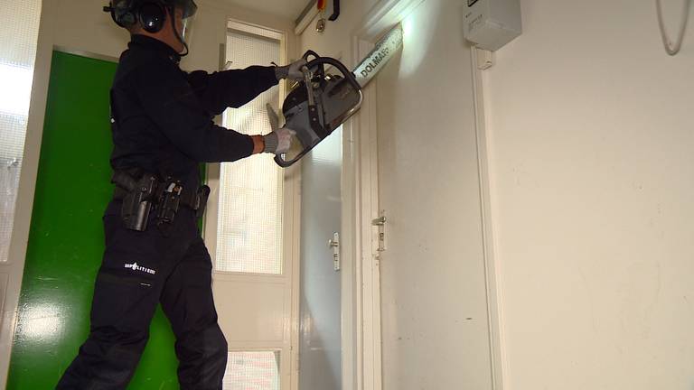 Agent sloopt een deur in het oude studentenhuis