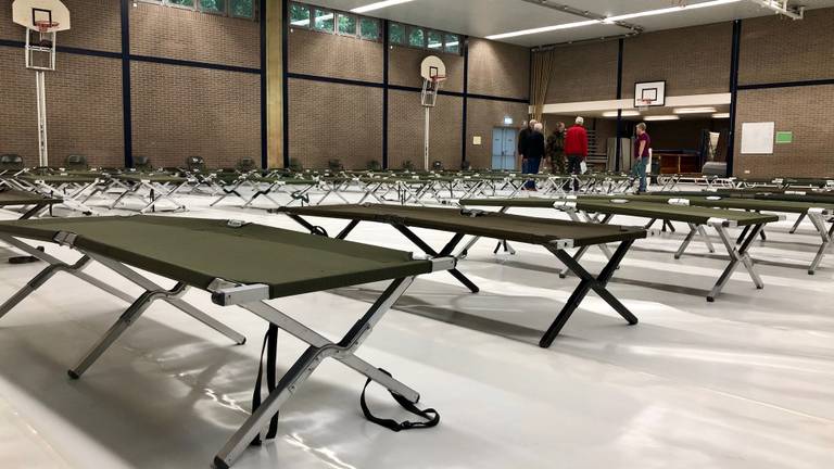 Vrijwilligers zetten maandag tientallen veldbedden in de gymzaal van scholengemeenschap 't Rijks. (Foto: Erik Peeters)