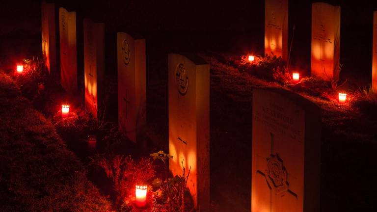 In het donker verlichten kaarsjes de oorlogsgraven in Overloon. (Foto: Albert Hendriks)
