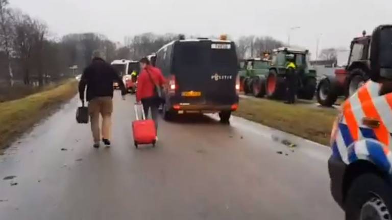 Mensen moeten extra lopen, tussen politiewagens en trekkers door, om hun vlucht te halen (foto: Noël van Hooft).