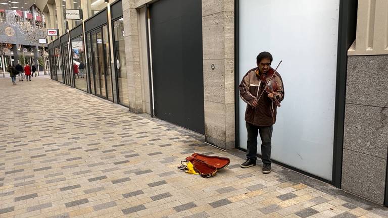 In Tilburg weet een straatmuzikant alsnog wat geld te verdienen (foto: Jan Peels).