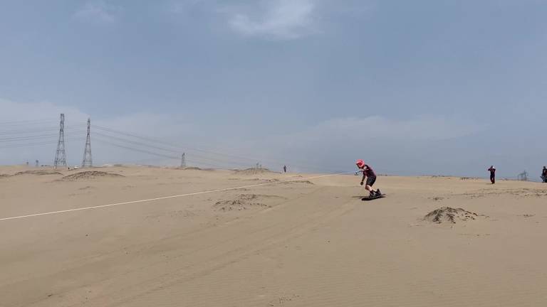 Brandweermannen snowboarden door de Peruaanse duinen.