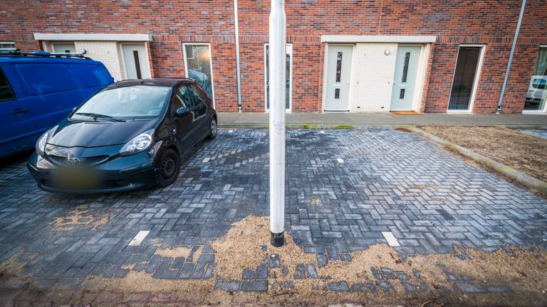 Een lantaarnpaal midden in een parkeervak