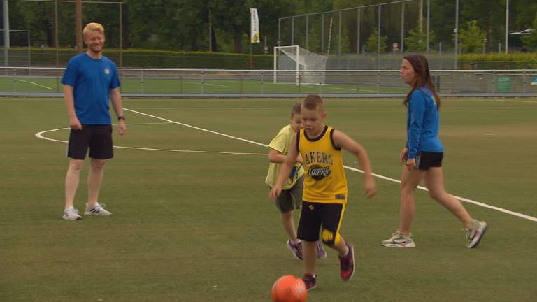 Twee leraren spelen een potje voetbal met de kinderen op de Sportstuif in Best.