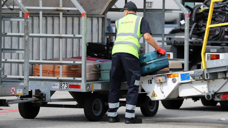 Een medewerker van Skytanking laadt koffers uit het ruim (foto: Collin Beijk).