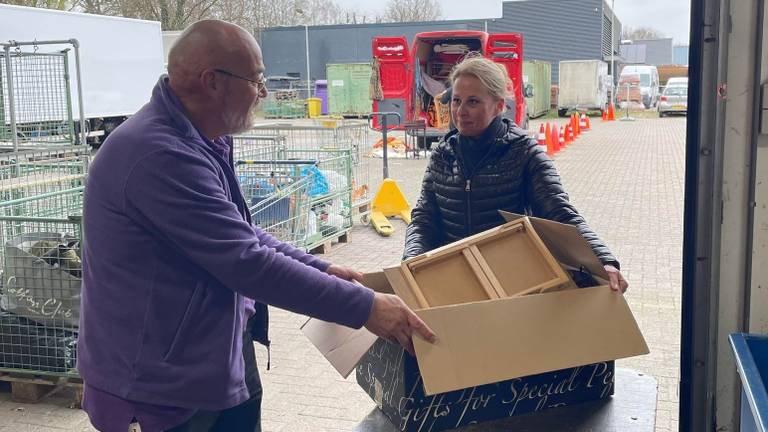 Een vrouw brengt een doos tweedehands spullen naar de kringloop in Schijndel