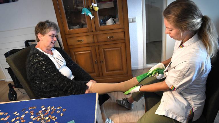 Een thuiszorgmedewerker helpt met steunkousen (Foto: ANP)