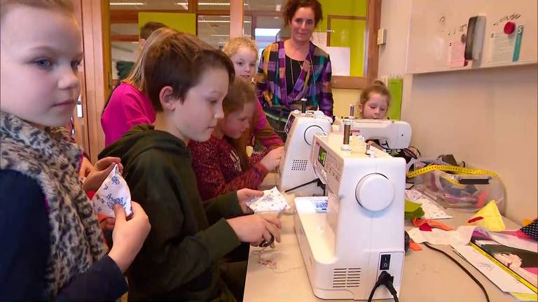 Basisschoolleerlingen krijgen les in muziek en naaien van gastdocenten. 