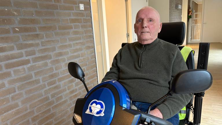 Johan van Haperen rijdt met zijn scootmobiel door de gang bij zijn appartement (foto: Erik Peeters)