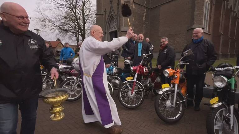 Een enthousiaste diaken Karel Bennenbroek zegent motoren en brommers onder de kerk in Mierlo.