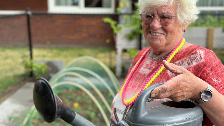 Bewoonster Mieke geeft de plantjes water in de moestuin.