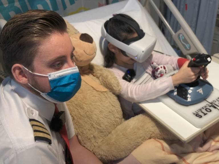 Piloot Mike geeft zieke Ruya (8) vliegles in Amphia Ziekenhuis.