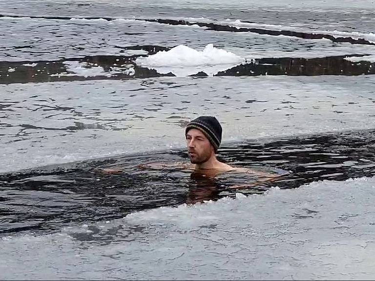 Jorg zwemt tussen het ijs.