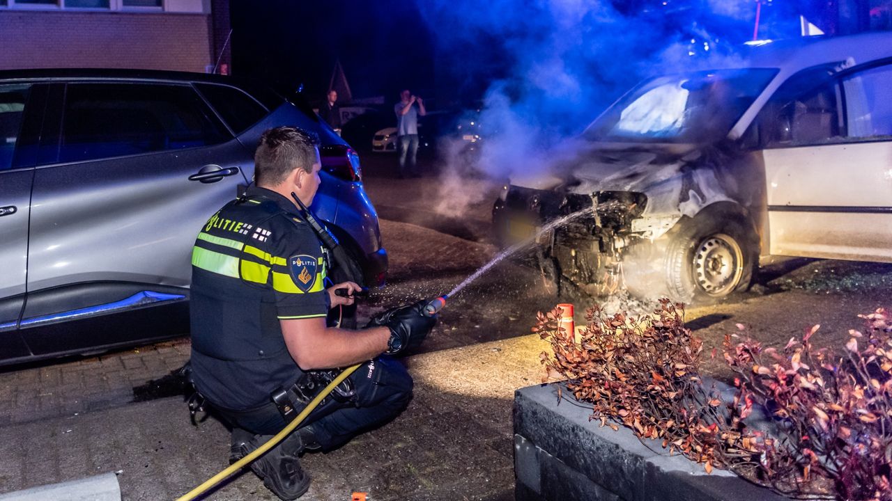 Een agent bluste de autobrand aan de Mullegenstraat in Tilburg (foto: Jack Brekelmans/SQ Vision).