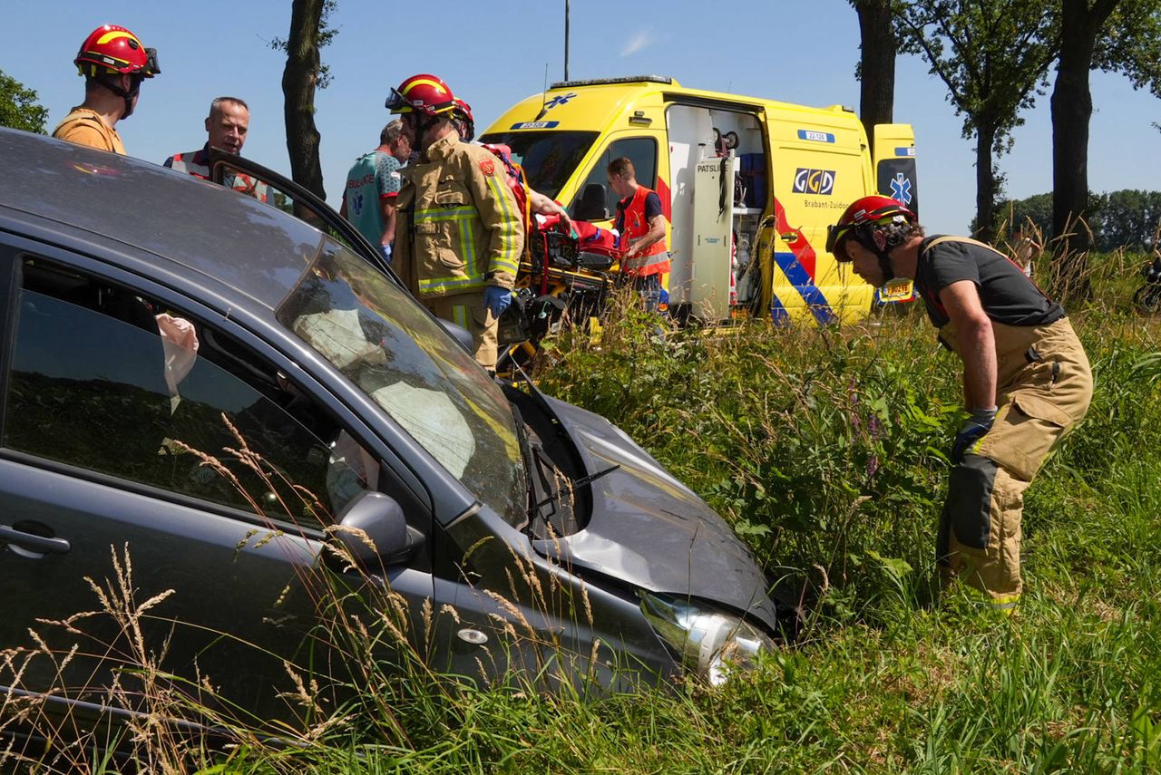 Terwijl ambulancepersoneel zich over het slachtoffer buigt, bekijken brandweerlieden de schade aan de auto (foto: Harrie Grijseels/Persbureau Heitink).