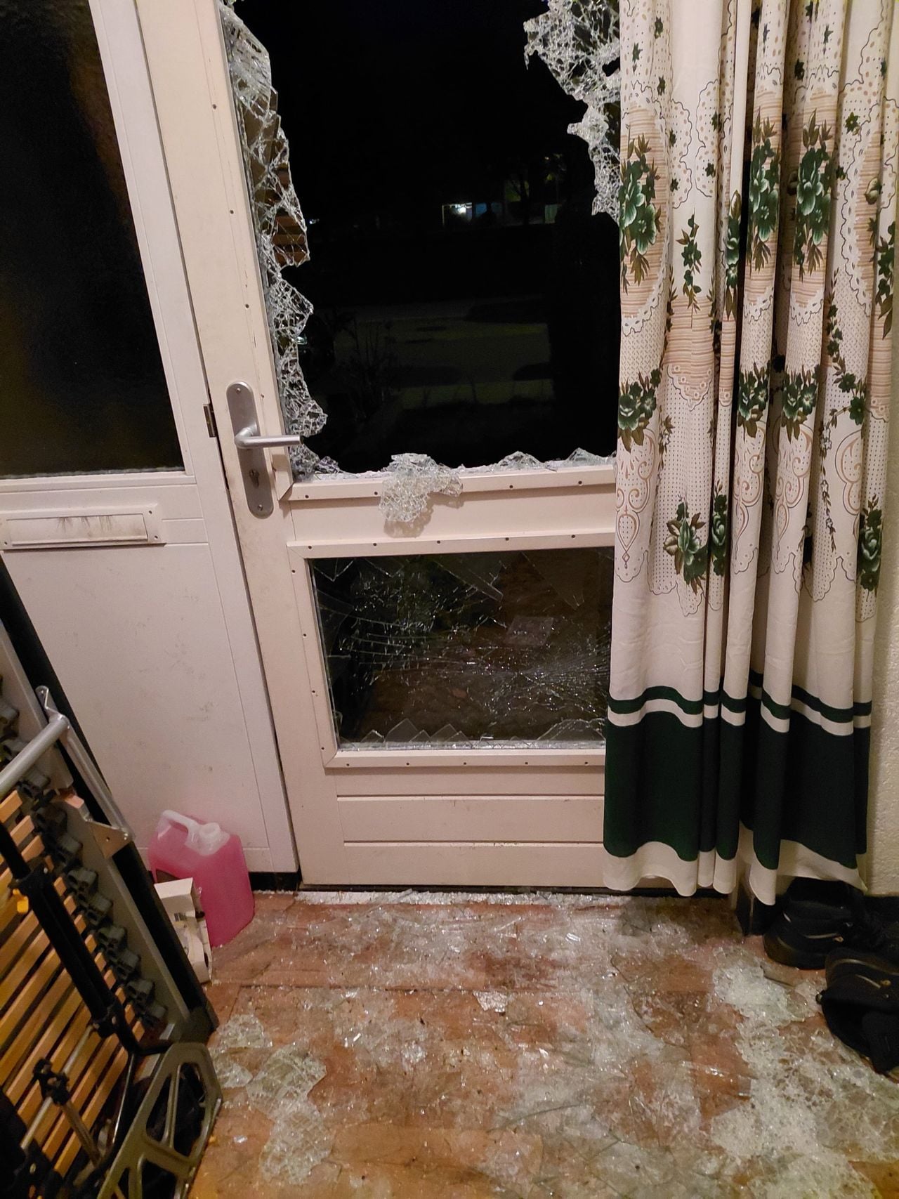 Glasscherven in de gang nadat de politie het raam van de voordeur insloeg (foto: privé).