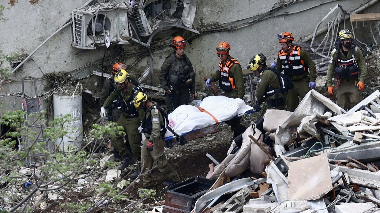 Hulpverleners bergen een lichaam bij het verwoeste gebouw in Haifa - EPA