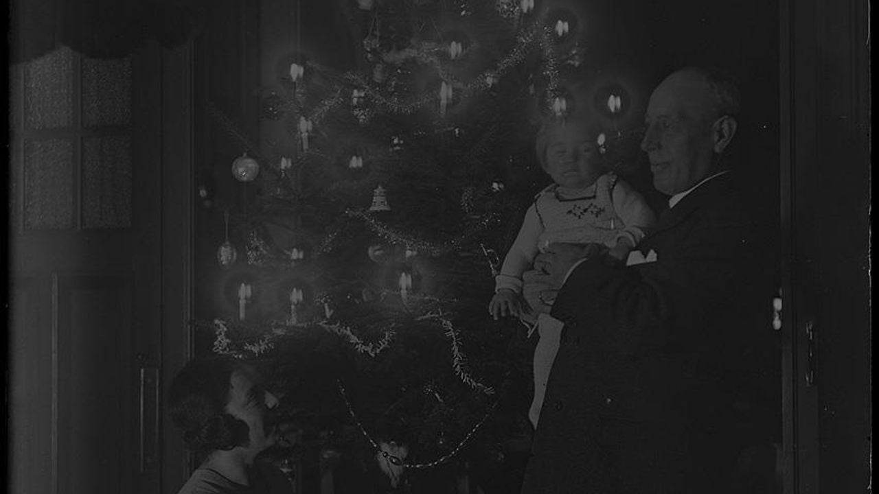 Jo Halbertsma kijkt omhoog naar een man en kindje naast de kerstboom. De foto is genomen tussen 1920-1925 (foto: Stedelijk Museum Breda).