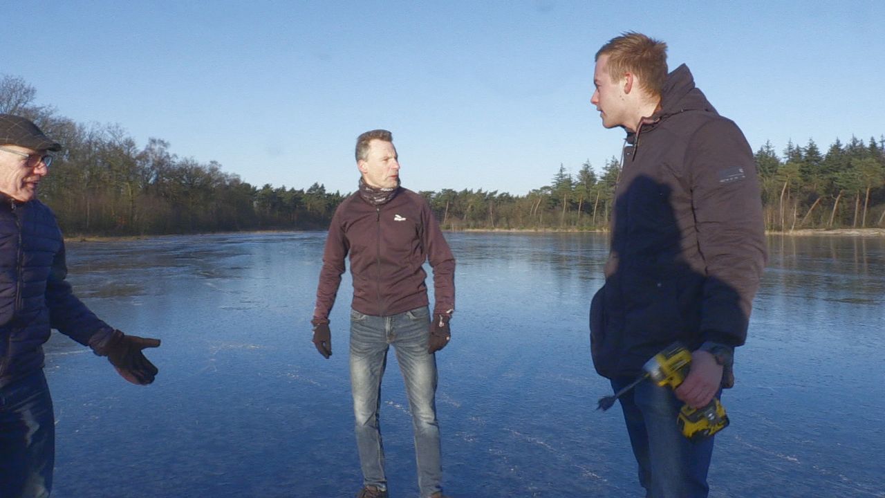 Hans en twee andere schaatsliefhebbers meten hoe dik het ijs is. 