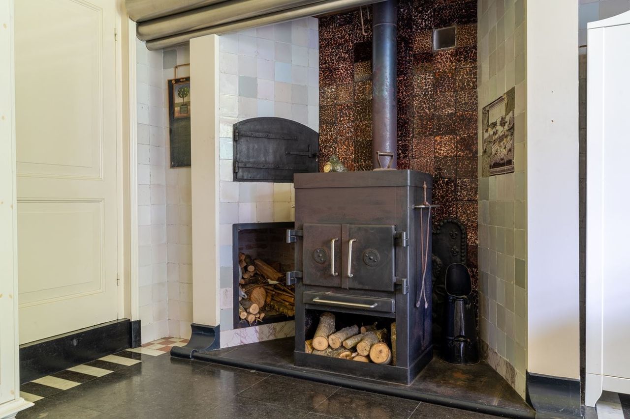 De meer dan honderd jaar oude schouw, met antieke schildpadtegels erachter (foto: Makelaars van Altena).