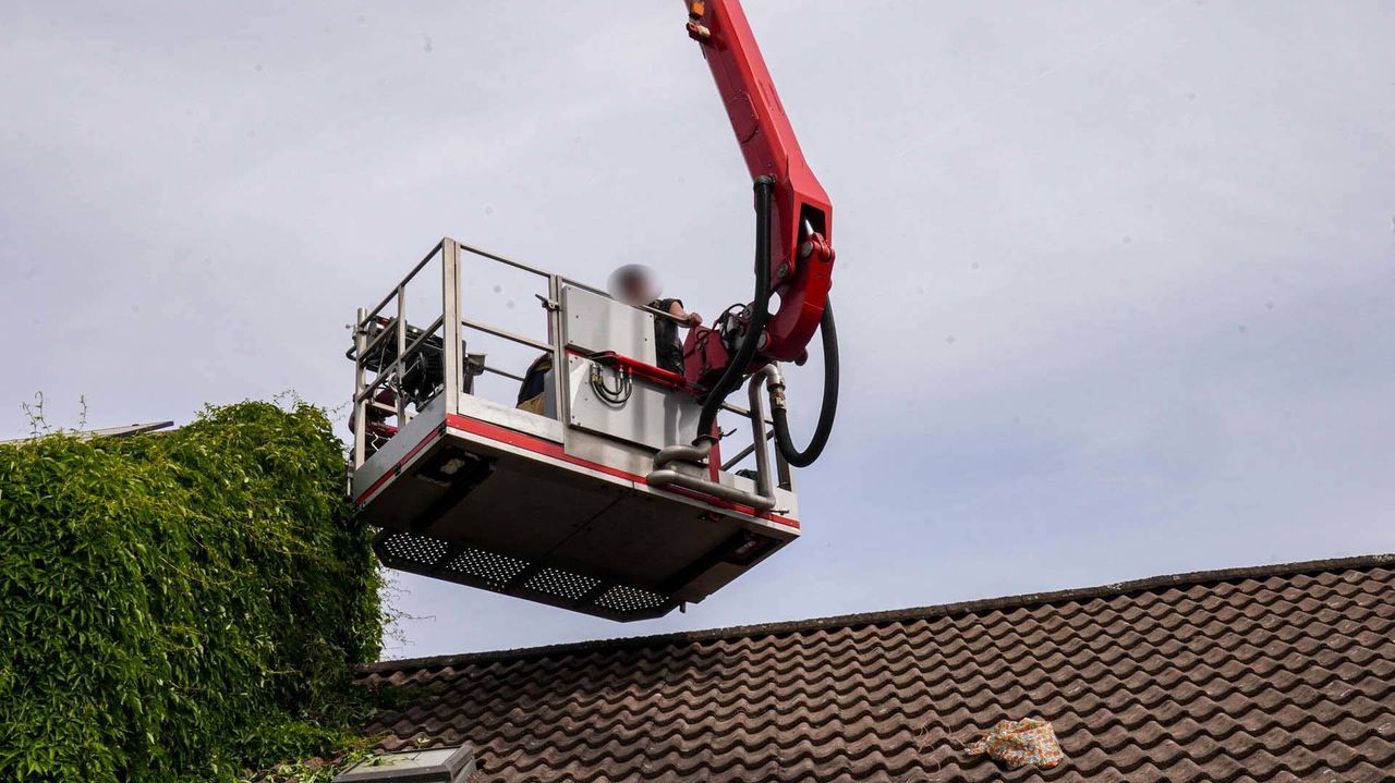 De vrouw is met een hoogwerker van het dak gehaald (foto: Harrie Grijseels/Persbureau Heitink).
