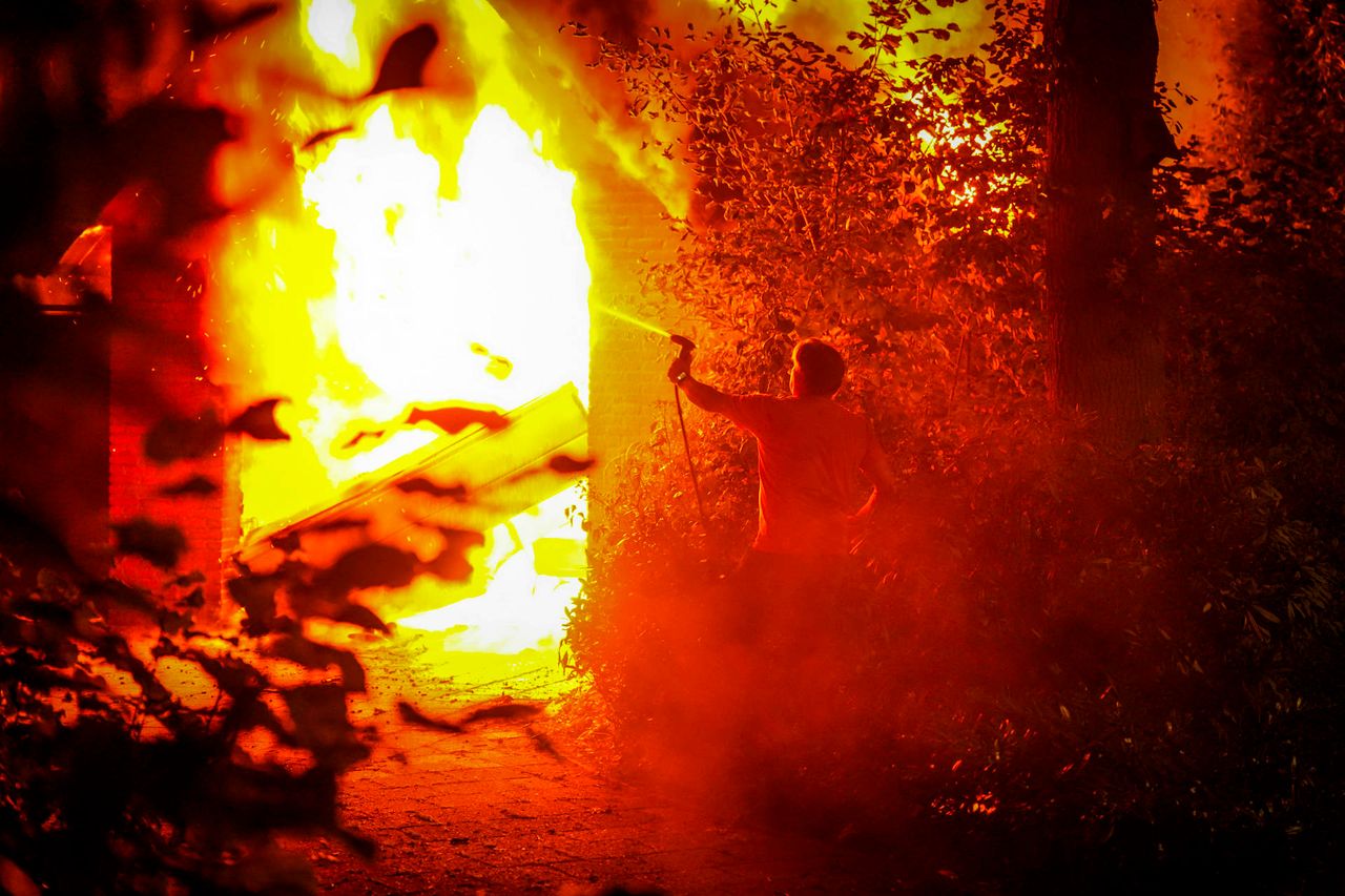 De buurman probeert nog te blussen met een tuinslang (foto: Persbureau Heitink).