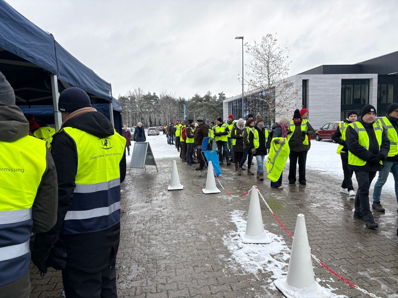 Mensen krijgen veiligheidshesjes en een zoekstok uitgedeeld en worden ingedeeld in groepjes (foto: Wilco Zonneveld).