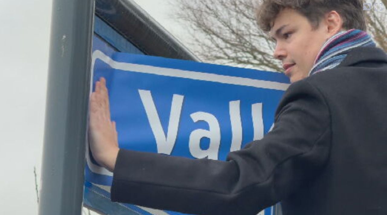 Van de Plas plakt de sticker op het bord.