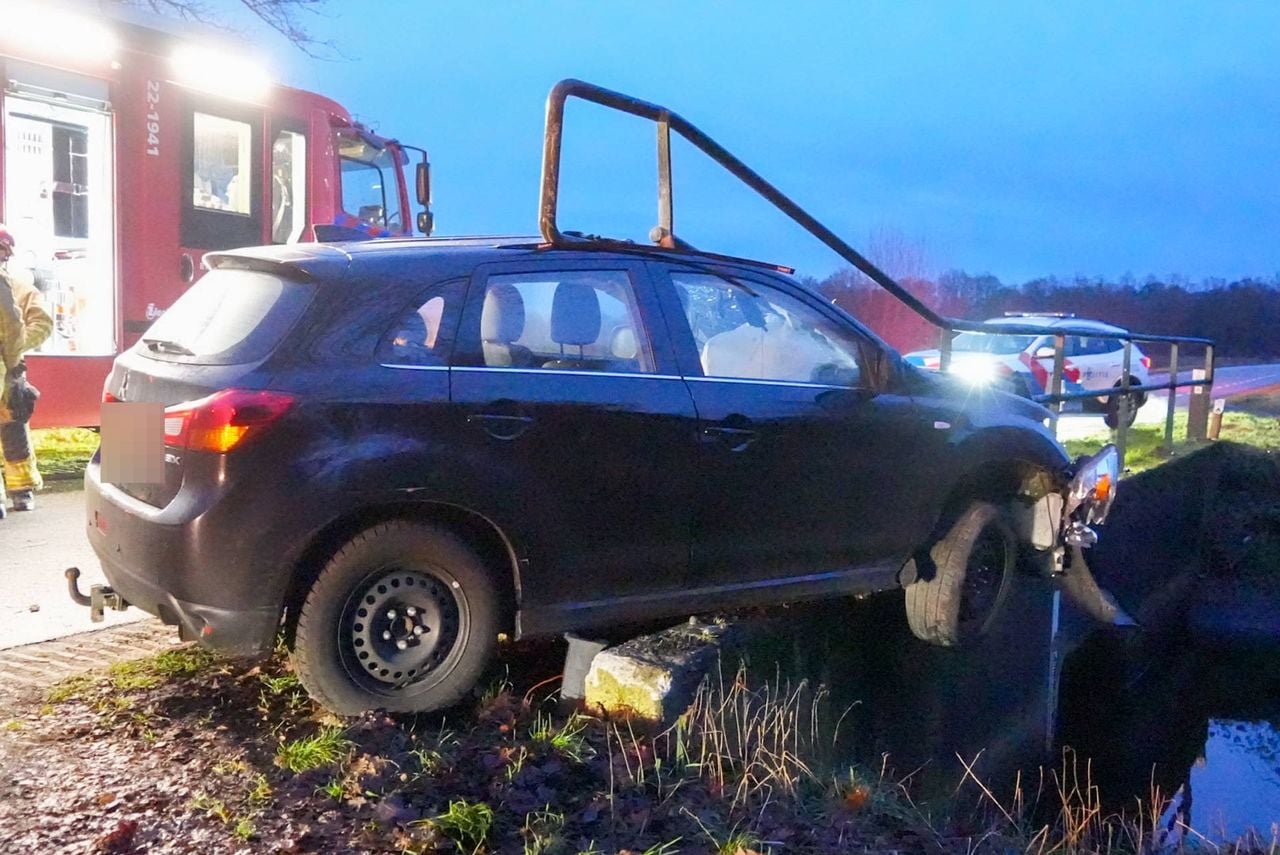 De auto hangt deels boven het water (foto: Harrie Gijseels/Persbureau Heitink).