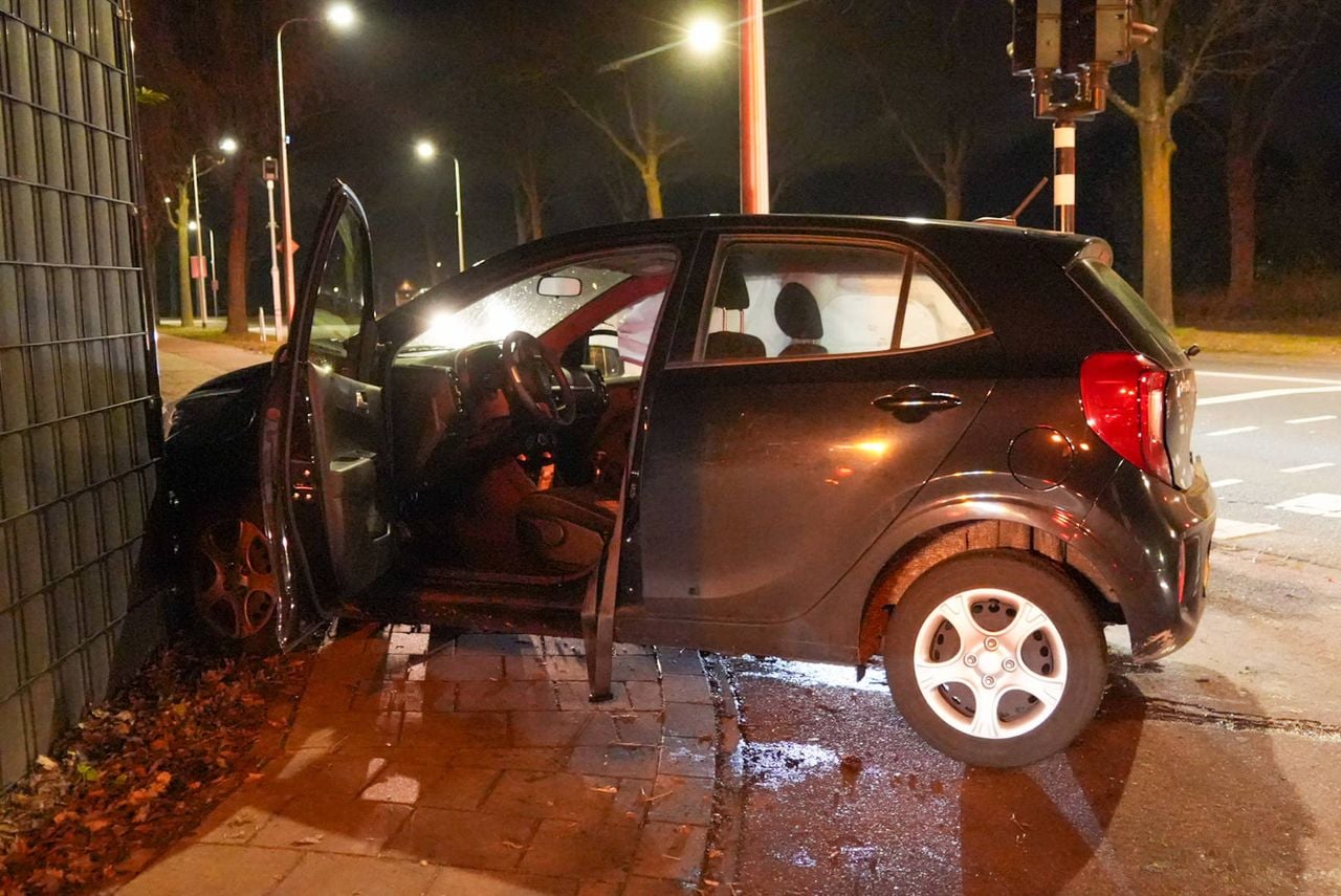 De auto kwam tot stilstand tegen een hek op het kruispunt in Helmond (foto: Harrie Grijseels/Persbureau Heitink).