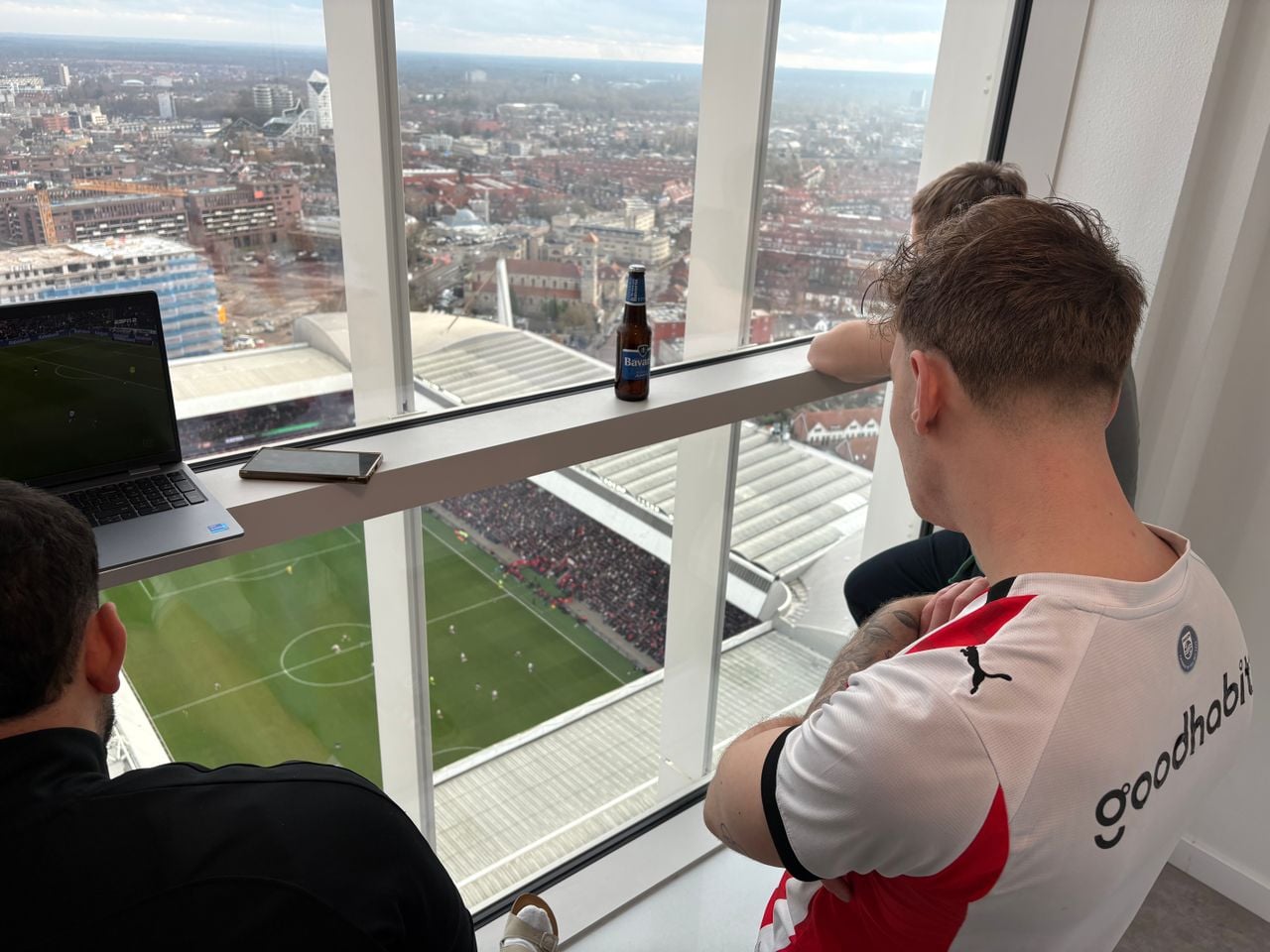 Een groep vrienden kijkt vanuit een appartementencomplex recht op het veld van PSV (foto: Wilco Zonneveld).