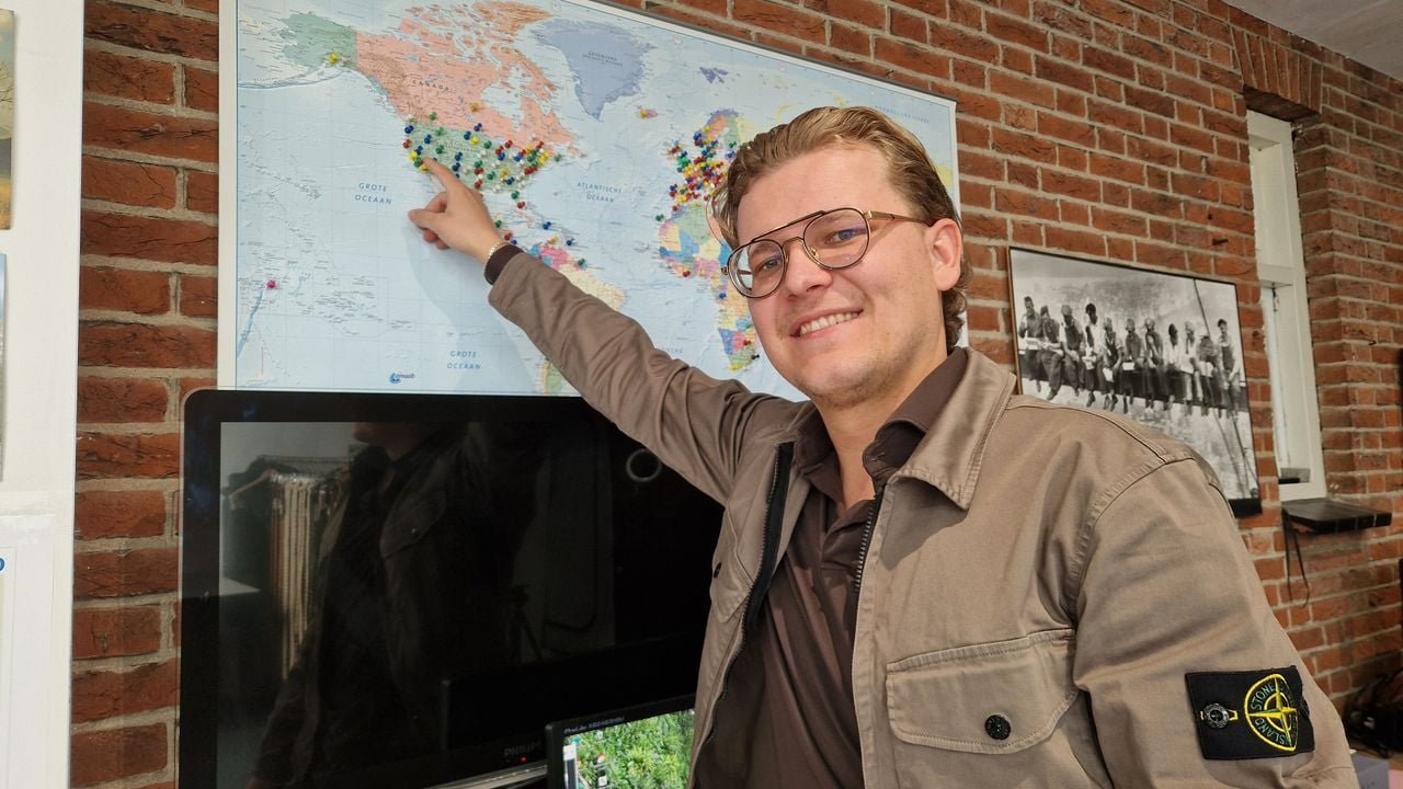 Thomas bij de wereldkaart op zijn kantoor met punaises van plekken waar er klanten van de kledingwinkel zijn (foto: Tom Berkers).