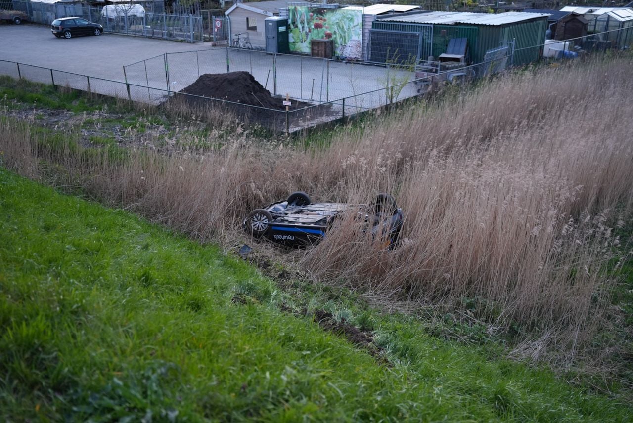 De auto belandde onderaan de dijk in een sloot in Waalwijk (foto: Erik Haverhals / Persbureau Heitink).