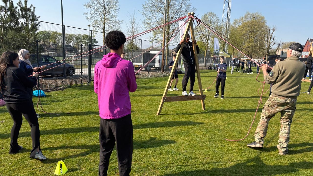 Jongeren werken samen om een steltloper naar de overkant te krijgen.