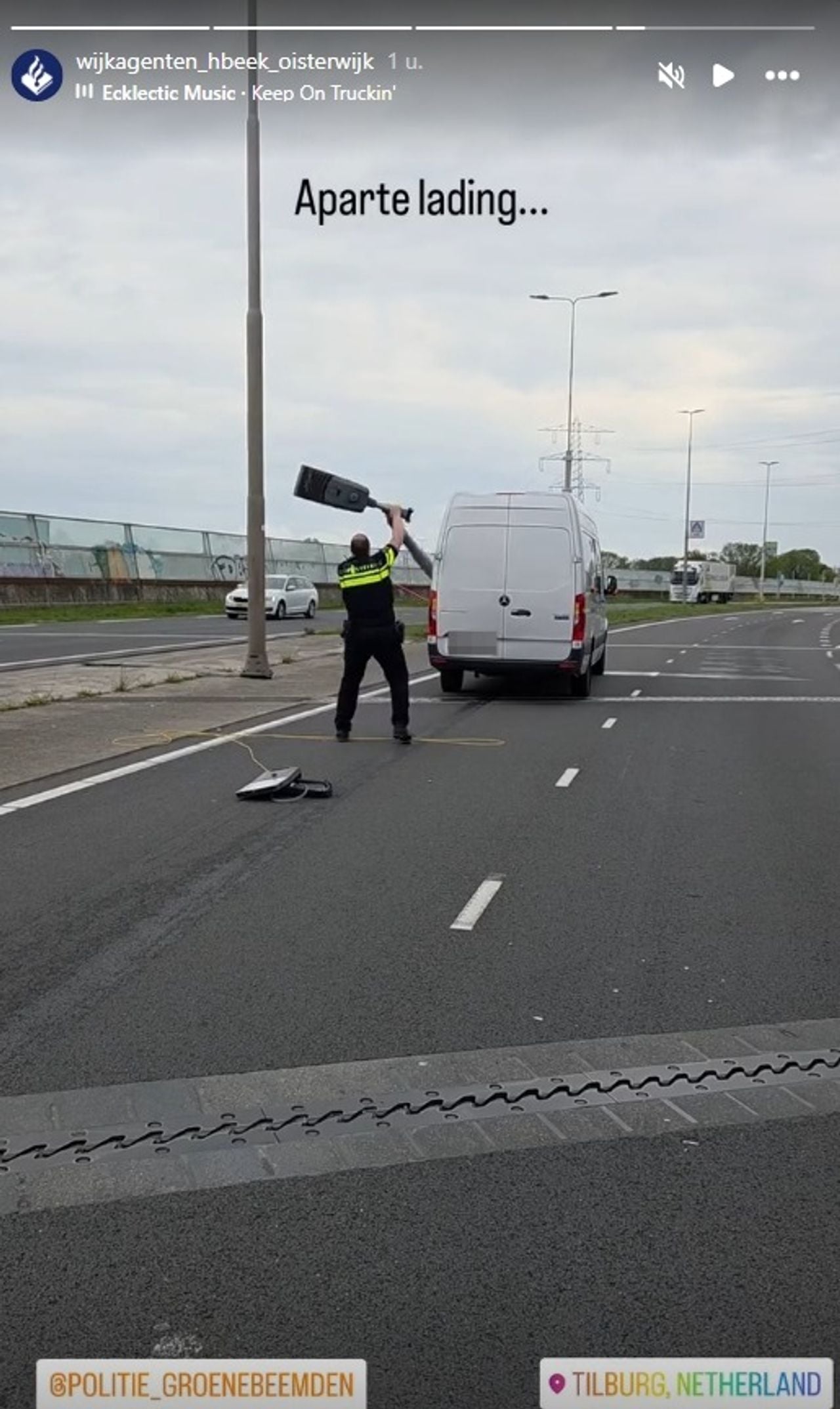 Een politieagent haalt de lantaarnpaal van de auto (foto: wijkagenten Hilvarenbeek en Oisterwijk).
