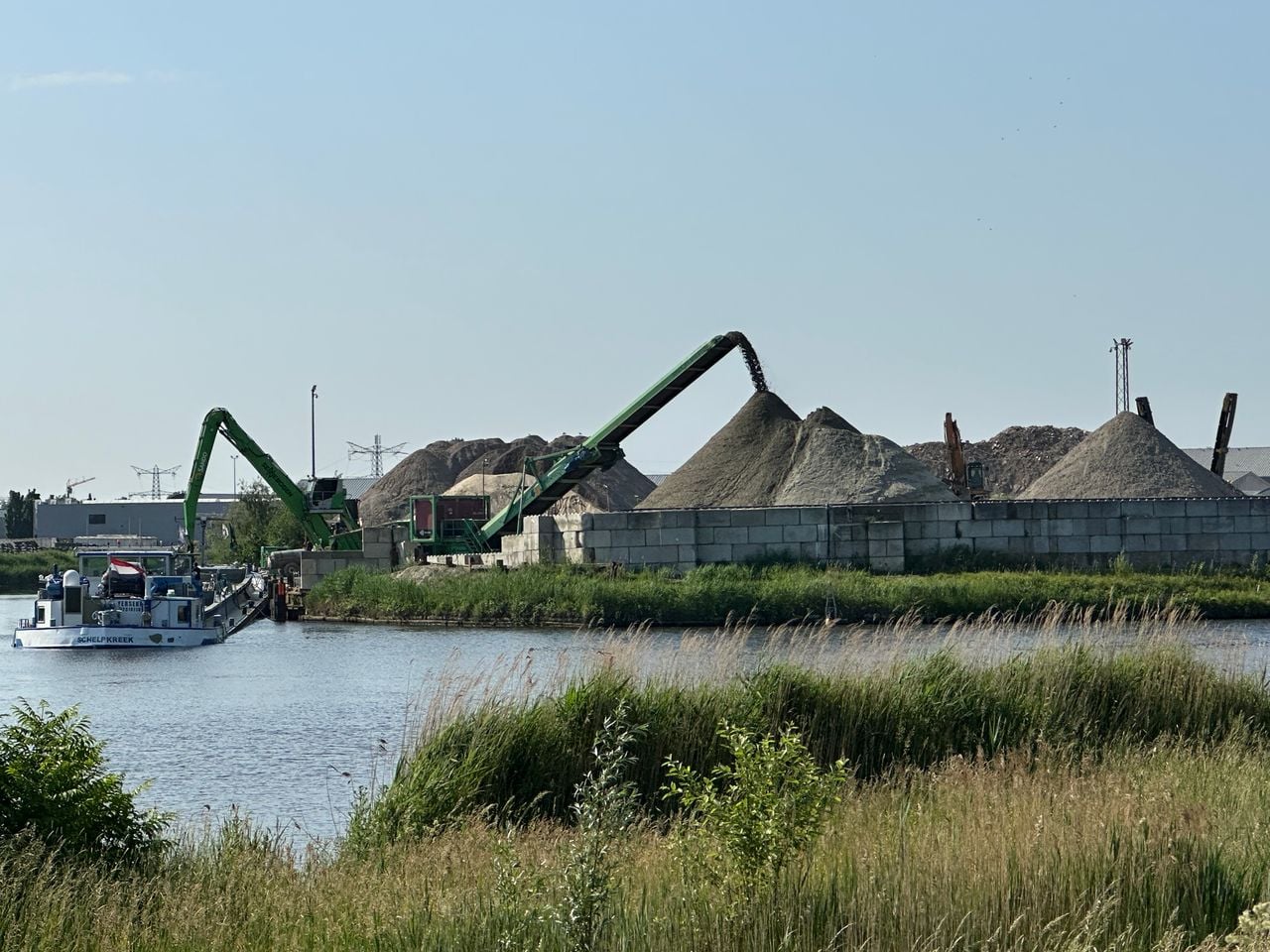 Afval wordt van de boot naar het bedrijventerrein overgeladen.