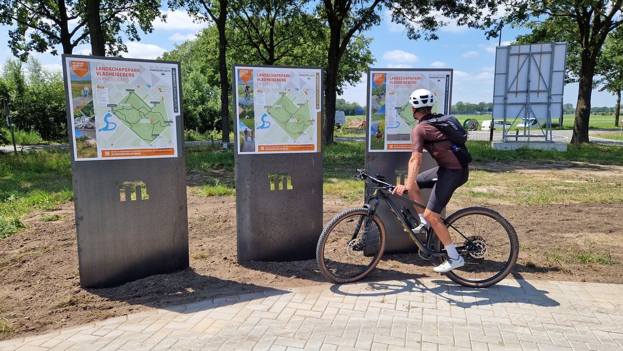 Een wielrenner bij de verschillende informatieborden die rond de Vlagheideberg staan (foto: Tom Berkers).