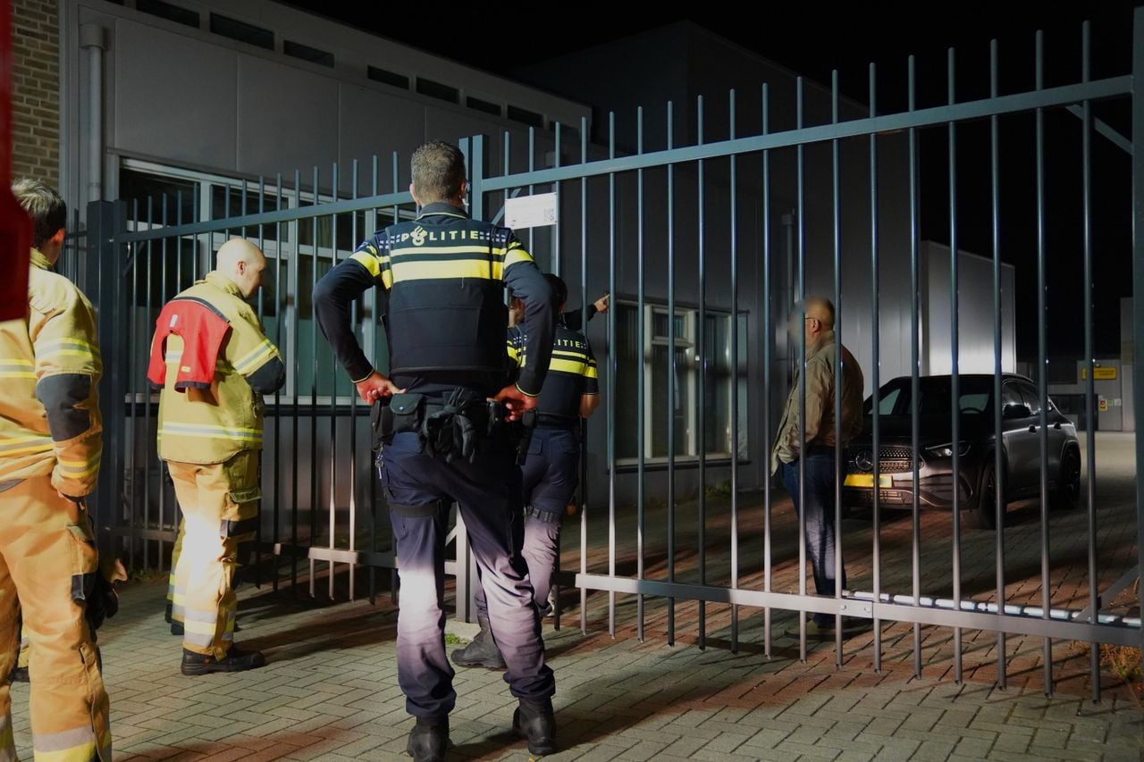 Twee mannen klimmen over de kapotte poort van een parkeerplaats aan de Industrieweg in Vught (foto: Bart Meesters/Persbureau Heitink).
