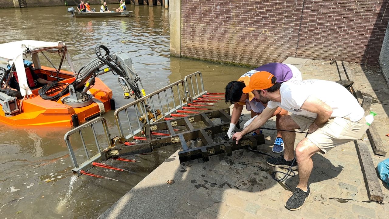 Wethouder Jeroen Bruijns en directeur Birgitte van Beurden slepen een hekwerk uit het water (foto: Ronald Sträter).