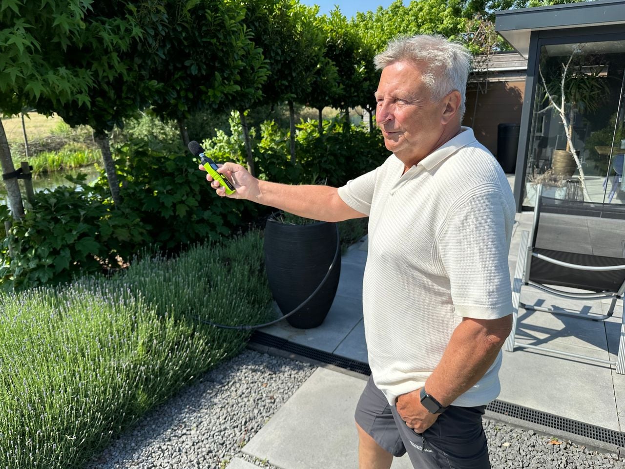 Ed Graman in zijn tuin met een decibelmeter.