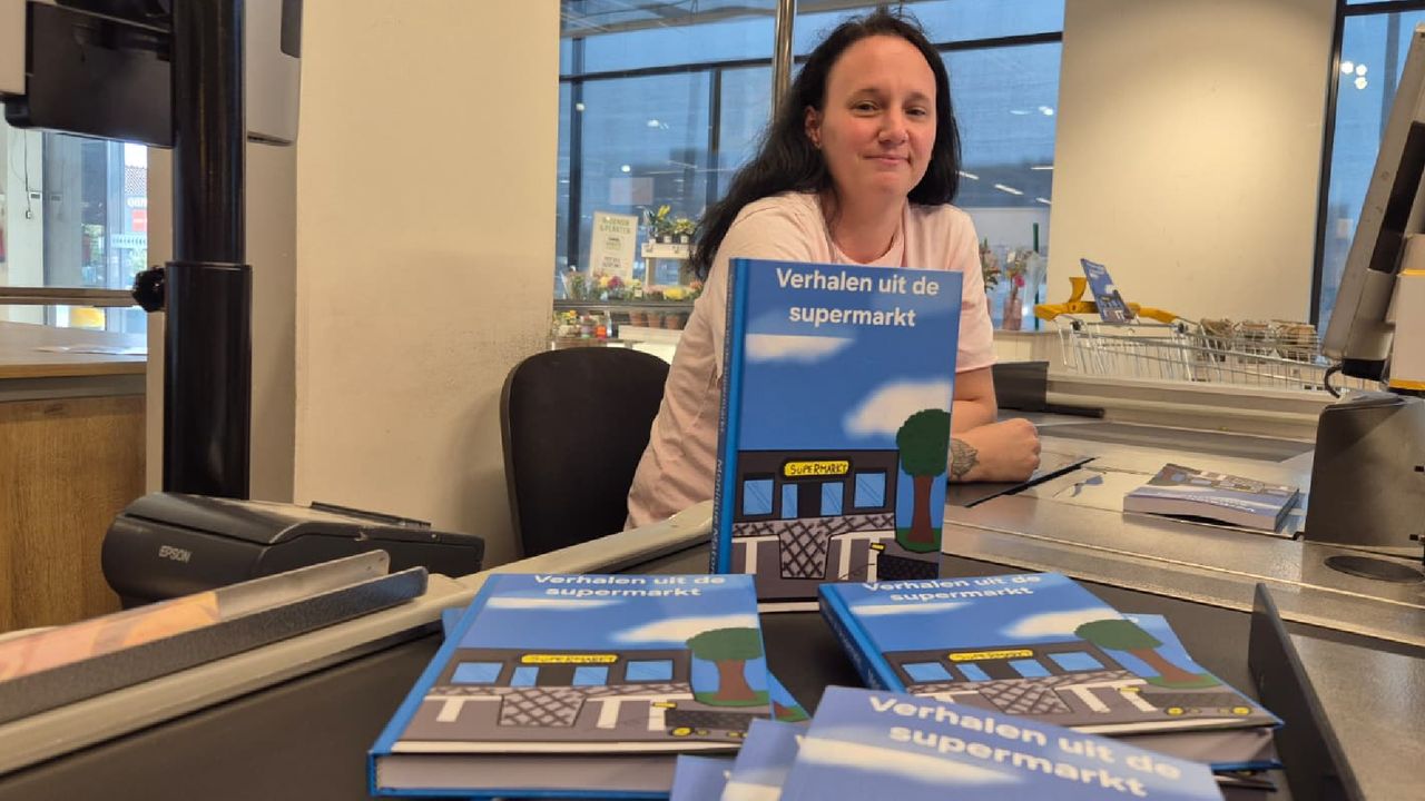 Monique met haar boek achter de kassa van de supermarkt (foto: Niek de Bruijn).