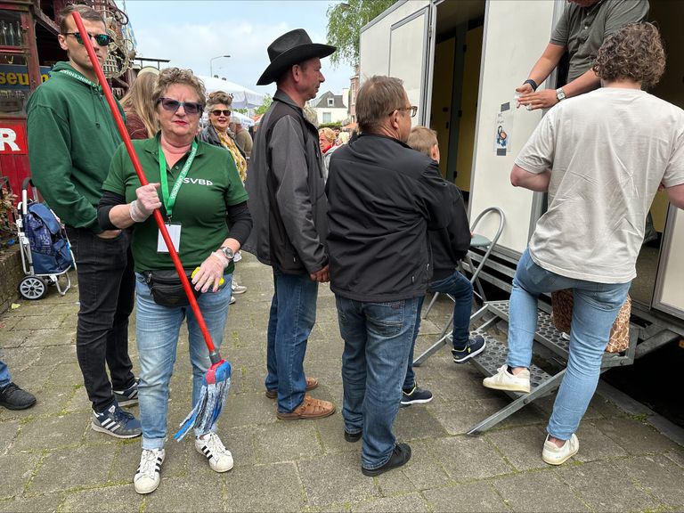 Ingrid voor haar toiletwagen op de vrijmarkt.