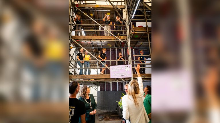 Burgemeester Joyce Vermue (tweede van links) en koningin Máxima groeten mensen die aan een wagen aan het bouwen zijn (foto: Eefje Fotografie).