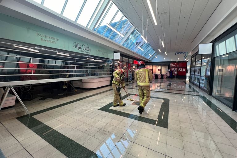 Brandweerlieden werken het water weg nadat sprinklerinstallaties in een winkelcentrum waren afgegaan (foto: SQ Vision).