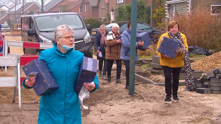 De dames brengen de kerstpakketten langs de deuren.